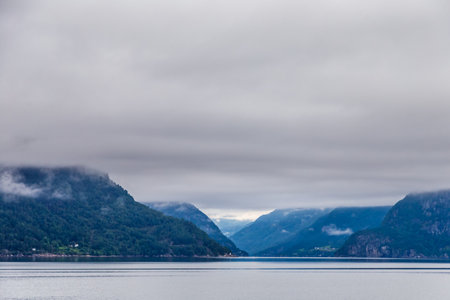 Majestic Norwegian Fjord: A Captivating Landscape Under Grey Skies Capturing Natures Tranquility and Grandeur in a Mystical Coastal Scene from the Heart of Norwayの写真素材