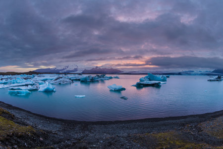 Breathtaking Glacier Lagoon at Sunset, Showcasing Icebergs and Reflective Waters in a Majestic...