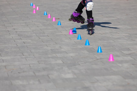 A Young Skater Practicing Skills on Rollerblades Among Colorful Cones on a Smooth Paved Surface in an Outdoor Setting, Perfect for Fitness and Fun Activitiesの写真素材