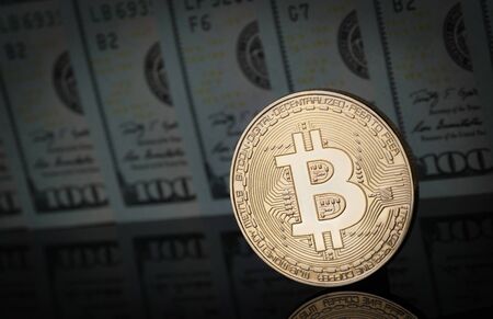 Bitcoin is on a dark surface, and in the background are dollar bills