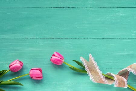 Festive background. Pink tulips on a turquoise wooden table. Top view, flat lay, copy space.の写真素材
