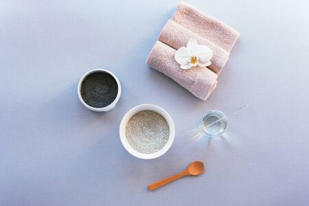 Black and green clay, spoon and towel on light gray table. Ingredients for natural skin care. Top...