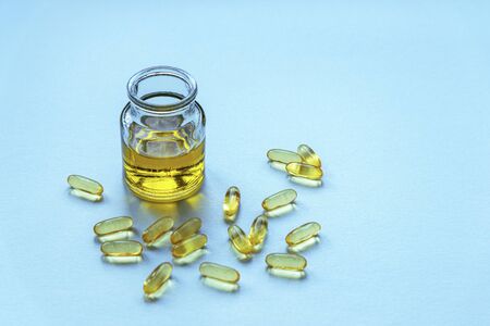 Natural fish oil in glass jar and capsules on blue background, top viewの写真素材