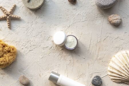 Face cream in white jar, natural soap, sea sponge and pumice stone on white plaster background. Natural organic cosmetics and body care products flat lay.の写真素材