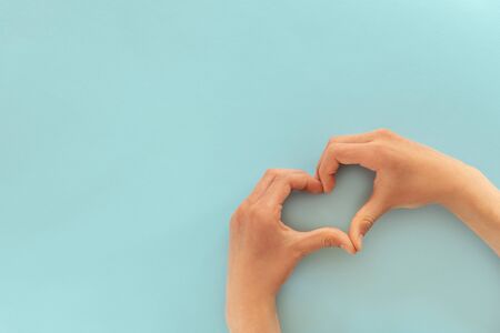 Heart shape made of child's palms on blue background, top viewの写真素材
