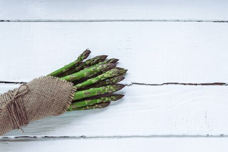 Green fresh asparagus on white wooden table. Healthy food concept. Top view, flat layの写真素材