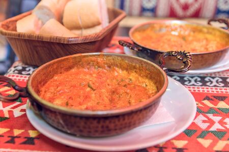 Traditional turkish food menemen in metal dishes on a multicolored tablecloth, selective focus.