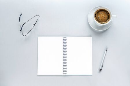 Cup of coffee and blank spiral notepad mockup on a grey background with pen and eyeglasses. Work from home concept. Top view, flat layの写真素材