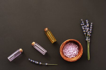 Lavender blossom, glass bottles with extract and essential oil, sea salt on black background, top view, flat lay, copy space.の写真素材