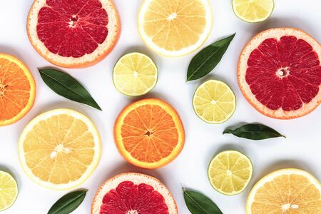 Various sliced citrus fruits: lime, orange, red and yellow grapefruit with green leaves on a white background, texture.の写真素材