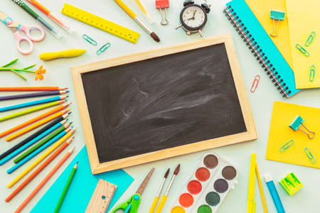 School supplies stationery, colour pencils, paints, alarm clock on light blue background. Back to school concept, top view, flat lay, copy spaceの写真素材