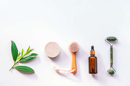 Modern apothecary, natural ingredients. Oil made of herbs, lavender soap, face roller and wooden brush, top view, flat lay, copy space.の写真素材