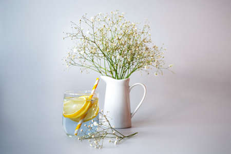 A glass of lemonade with straw and Gypsophila flowers in white jug, still life. Close upの写真素材