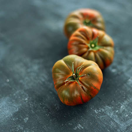 Green and red tomatoes on black background. Healthy food. Shallow depth of field.の写真素材