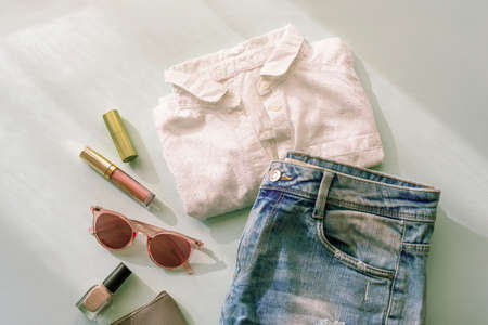 Women's summer fashion accessories, sunglasses, shorts, t-shirt, cosmetics in sunlight with shadows....