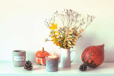 Autumn arrangement with pumpkin, candles, cones and yellow leaves in vase on white background.の写真素材