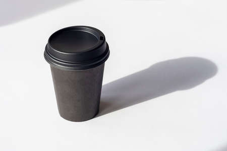 Disposable coffee cup on white table, sharp shadows.の写真素材