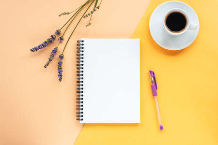 Mock up with blank notepad on yellow background with lavender flowers, coffee cup and pen. Top view, flat layの写真素材