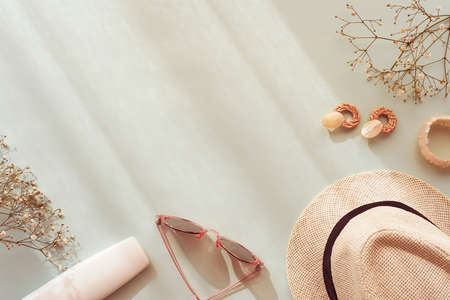 Female summer accessories on blue background. Sunglasses, straw hat, earrings, bracelet, cosmetic...
