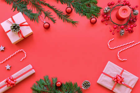 Christmas layout: candle, wreath, gifts in boxes, fir twigs, candy canes on red background, top view, flat lay, copy space.の写真素材
