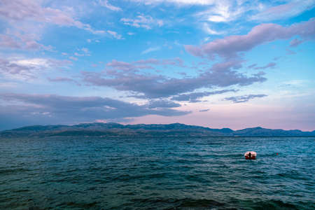 Beautiful seascape with mountains on the horizon and floating boat at sunset.の写真素材