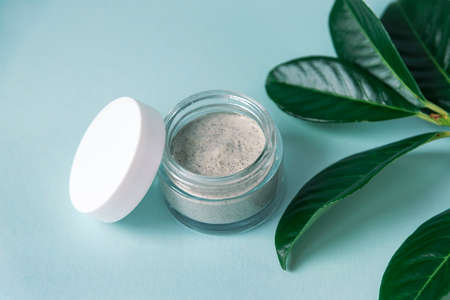 Natural handmade cosmetic cream jar with green leaves, light blue background. Bio organic cosmetics. Top view.の写真素材