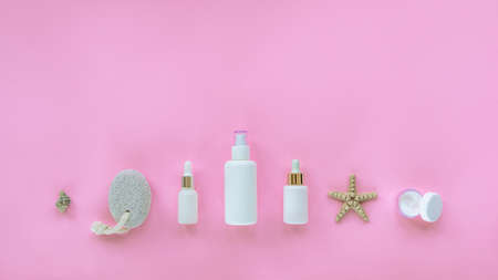 Natural organic beauty skincare products. Serum, cream jar, tonic, cosmetic oil in white unbranded bottles, pumice stone, seashell. Pink background, top view, flat lay, copy spaceの写真素材