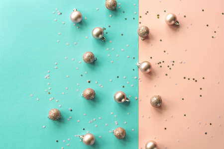 Christmas balls and confetti on a blue and pink background, New Year concept. Top view, flat lay,...