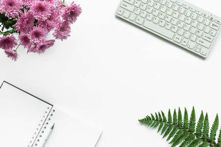 Notebook, pen, keyboard, bouquet of pink chrysanthemums and fern leaves on a white background. Woman workplace, top view, copy space.の写真素材