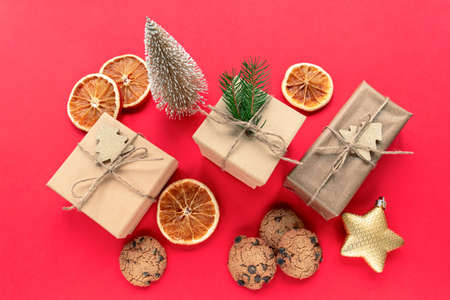 Christmas decorations, gift boxes, dried orange slices, baubles and homemade chocolate chip cookies on red background. Top view, flat lay.の写真素材