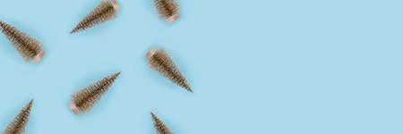 Christmas pattern of golden christmas trees on light blue background. Flat lay, top view, copy space.の写真素材