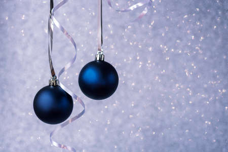 Two blue christmas balls on silver bokeh background. Minimal winter composition. New Year concept, copy space.の写真素材