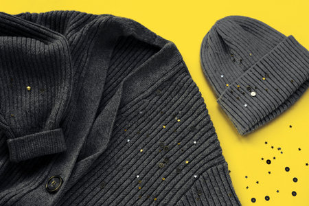 Gray cardigan sweater and cap on yellow background with confetti. Trendy colors of the year 2021. Top view, flat lay.の写真素材
