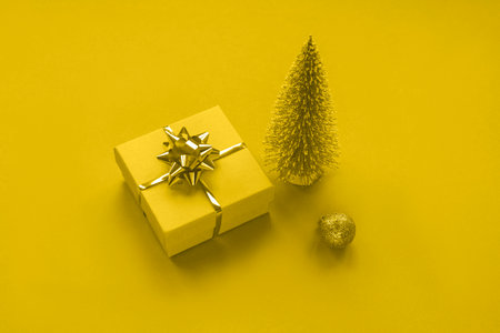 New Year's gift, Christmas tree toy and bauble on yellow background, toned in trendy 2021 color. Top view.の写真素材