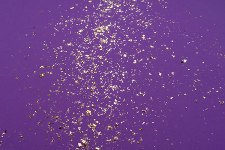 Shiny golden confetti on purple background. Top view, copy space.の写真素材