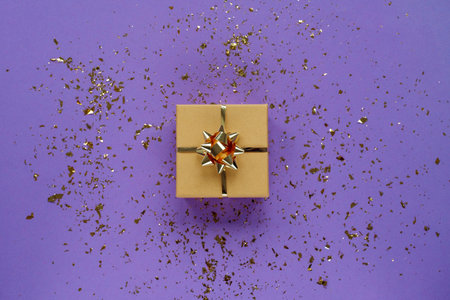 Gift in a box on purple background with confetti. Christmas concept. Top view, flat lay.の写真素材