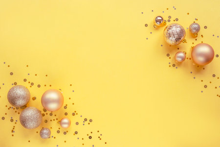 Christmas balls and confetti on yellow background. Festive New Year flat lay. Top view, copy space.の写真素材