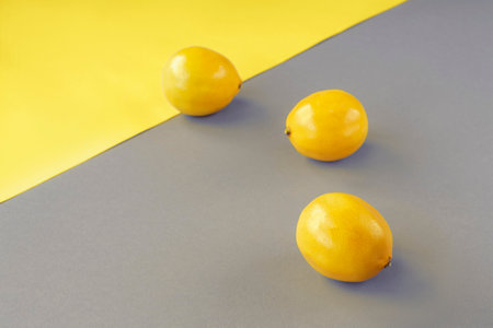 Lemons on yellow and gray background. Trendy colors 2021. Minimal composition, top view, copy space.