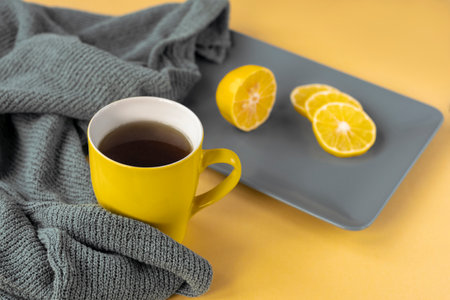 Yellow cup of tea and sliced lemon on gray plate. Trendy colors 2021, top view.の写真素材