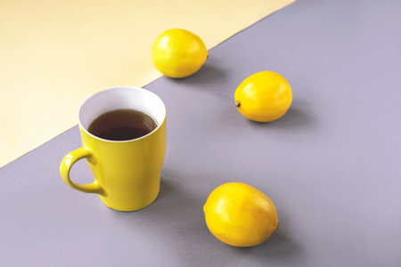 Yellow cup of tea and lemons on gray background. Trendy colors 2021.の写真素材