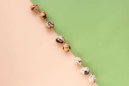 Quail eggs on a green and beige background. Easter concept. Top view, flat lay, copy space.の写真素材