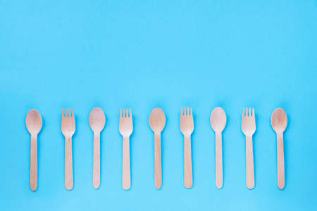 Disposable bamboo spoons and forks on blue background. Zero waste concept. Top view, flat lay, copy space.の写真素材