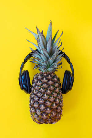 Pineapple in headphones on yellow background, top viewの写真素材