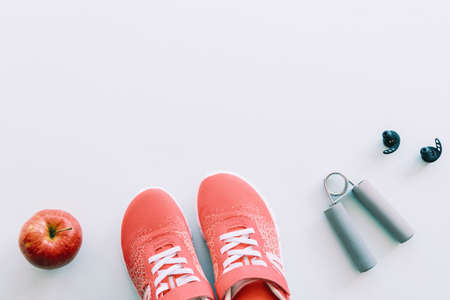 Red sneakers, sport tools and trainers, apple on blue background. Concept of healthy life and training, top view, flat lay, copy space.の写真素材