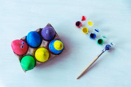 Painted eggs, paints and a paintbrush on a white table. Easter concept. Top view, flat lay.の写真素材