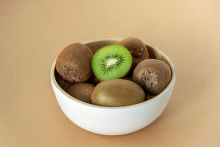Kiwi fruits in a white bowl on beige background. Healthy food concept. Close up.の写真素材
