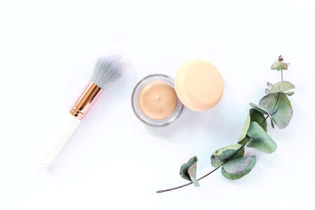 Concealer, make-up brush and green eucalyptus branch on white background. Top view, flat lay. Natural cosmetics conceptの写真素材