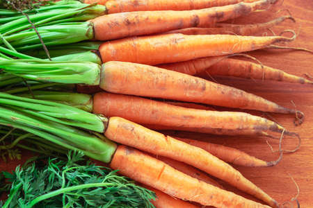 Fresh organic carrot with greenery on orange wooden table, top view, flat lay.の写真素材