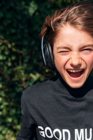 Girl child in a black sweatshirt with headphones listening to music and smiling.