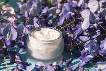 Cream jar and purple wisteria flowers background. Natural organic cosmetics conceptの写真素材